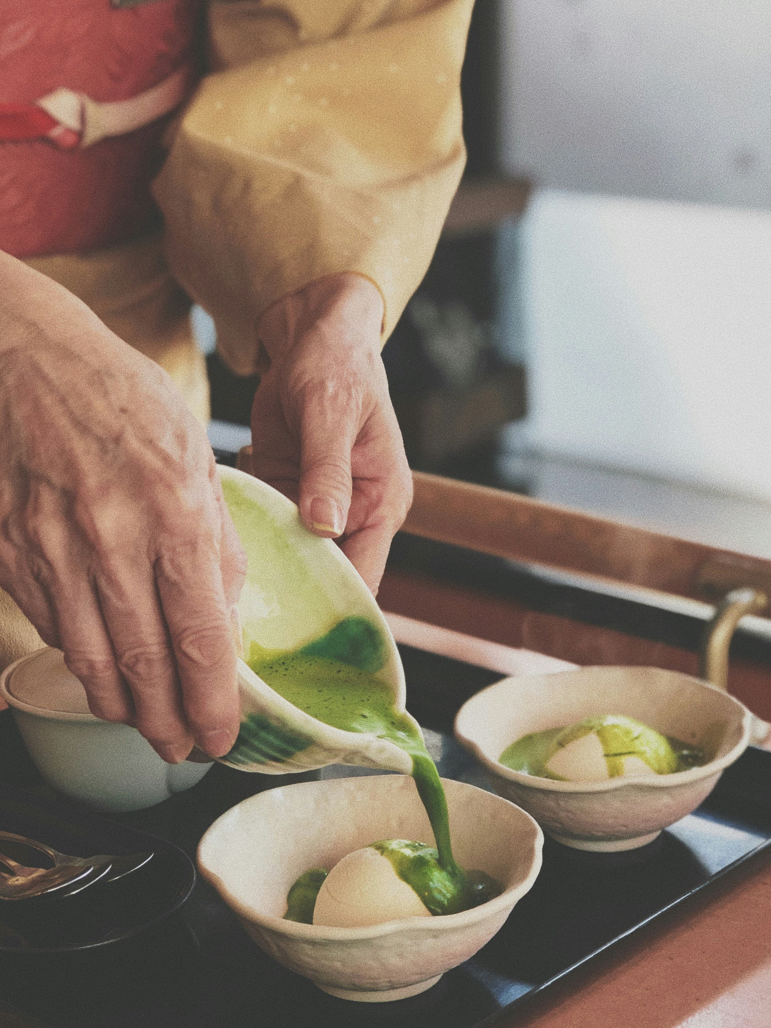 Matcha sauce being poured over mochi dessert