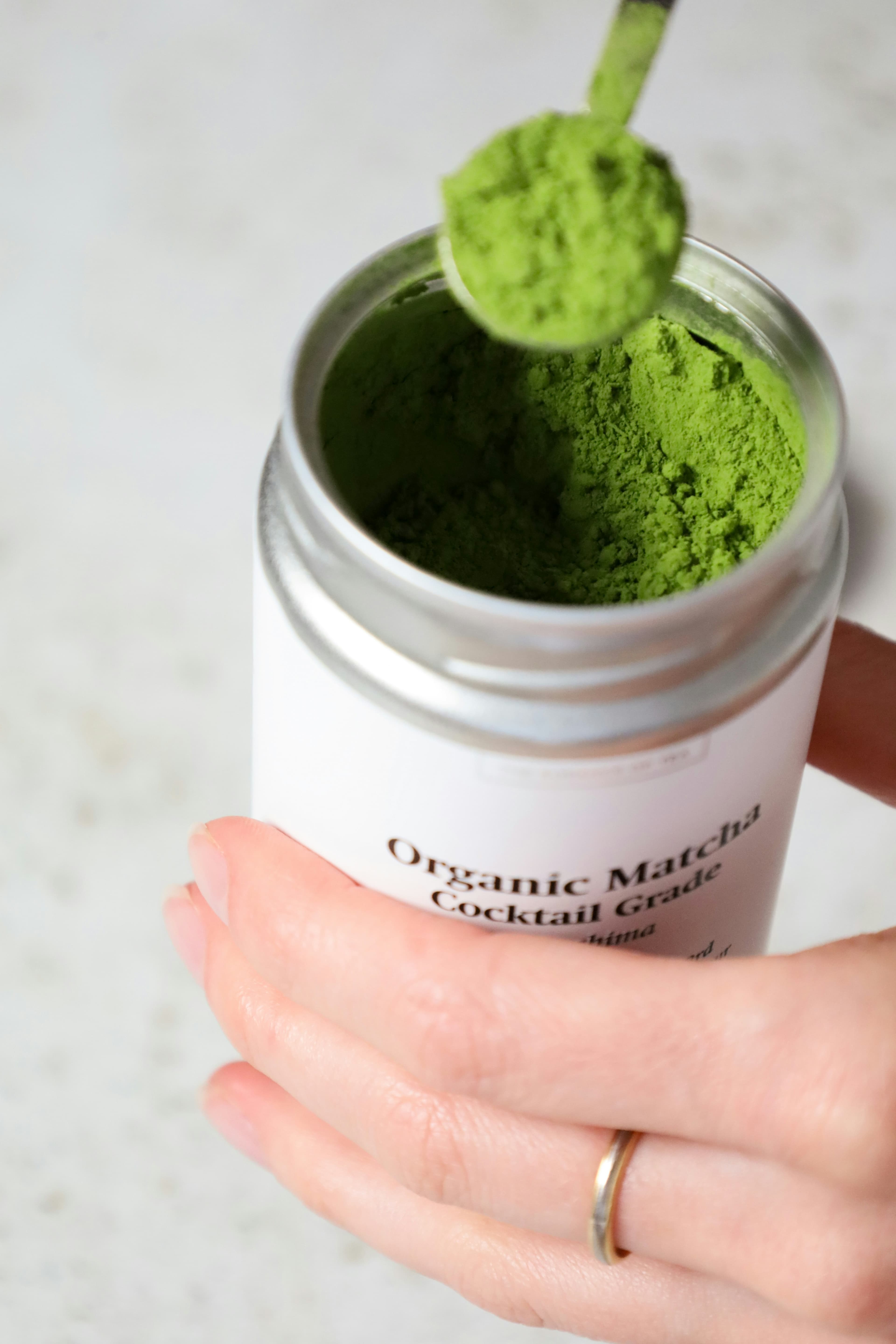 Hand holding matcha tin with scoop