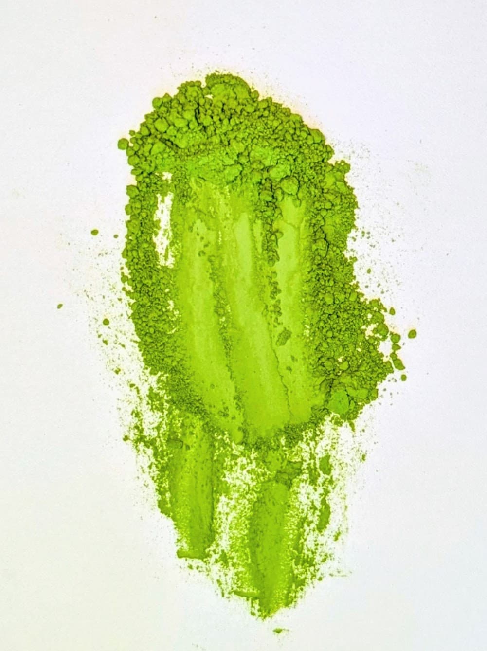 Vibrant green matcha powder spread on white background